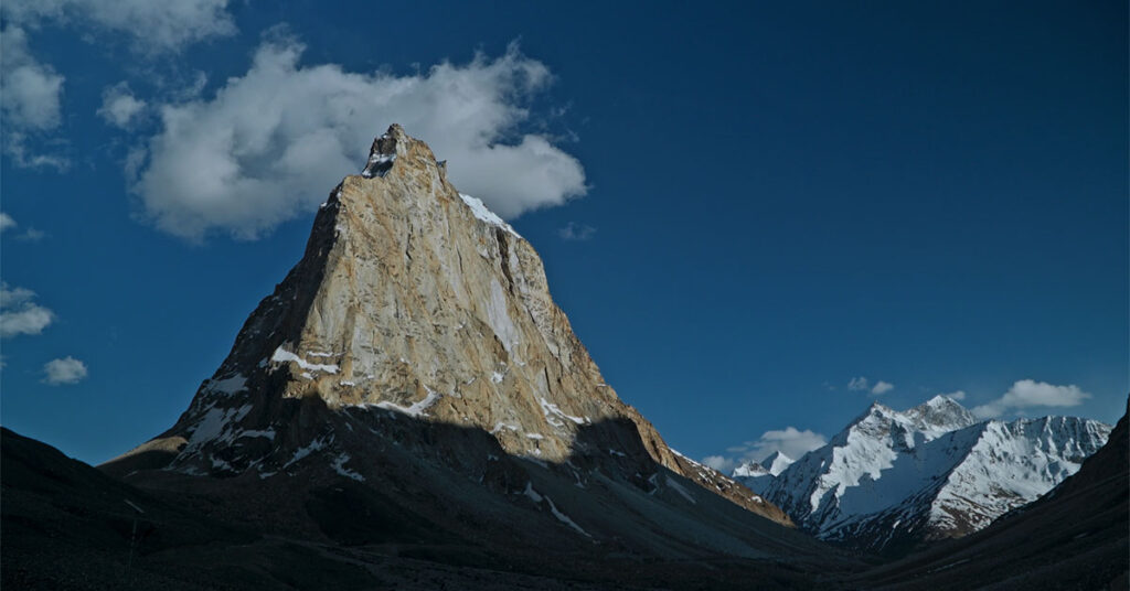 Towering Gonbo Rangjon peak rising sharply above snow-covered mountains in the remote landscapes of Zanskar Valley.