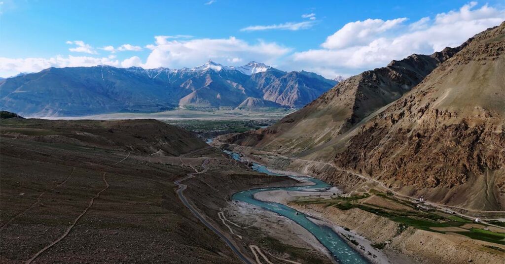 Scenic view of the turquoise Zanskar River winding through a vast mountain valley with rugged peaks and dramatic landscapes.