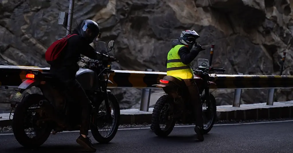 Bikers taking a break along a dramatic cliff road at Khab Sangam during a scenic Spiti bike trip