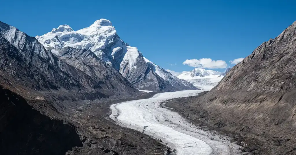 Scenic overlook of the massive, winding Drung Drung Glacier curving through a rugged Himalayan mountain pass near Pensi La, a famous natural landmark in Zanskar Valley, Ladakh.