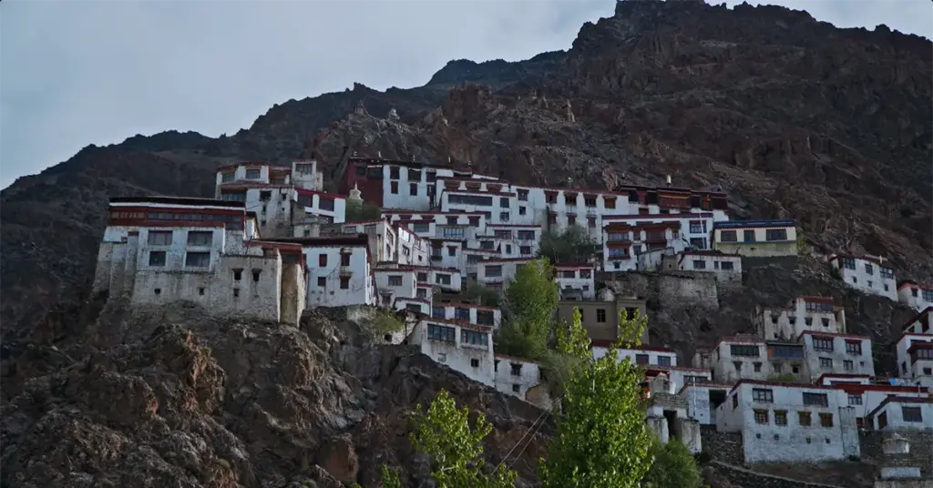 Wide angle view of the massive Karsha Monastery complex, a whitewashed Tibetan Buddhist gompa built into the steep rocky cliffs of the Zanskar Valley mountain range in Ladakh, India.