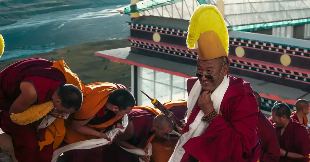 Smiling Buddhist monks wearing traditional robes and a yellow hat at Key Monastery.