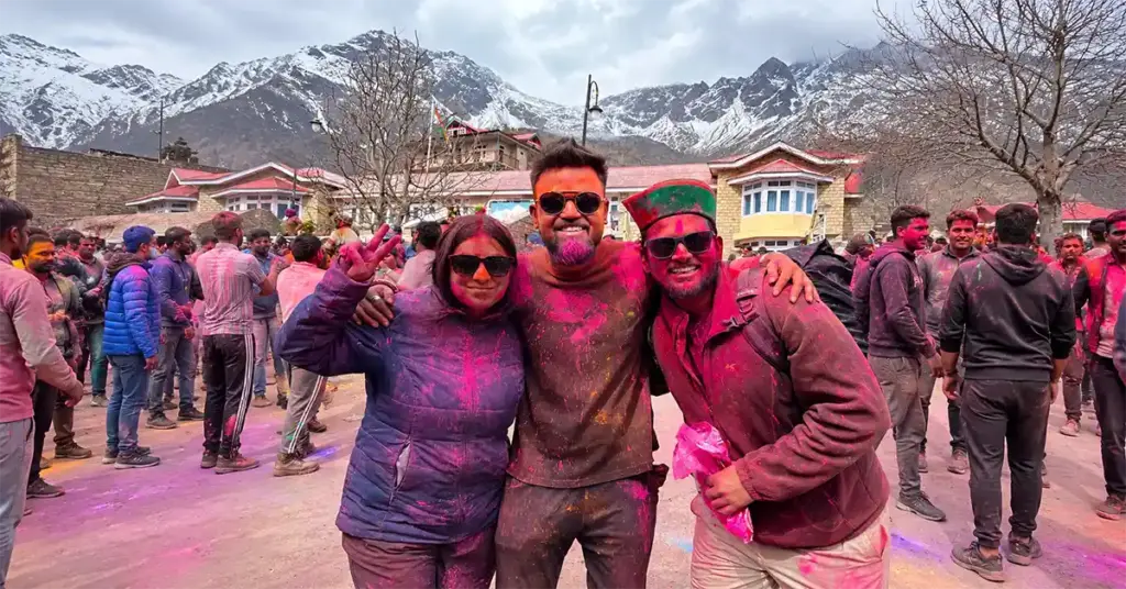 A group of friends covered in vibrant pink powder smiling during the traditional Sangla Holi festival celebration in the mountains of Himachal Pradesh.