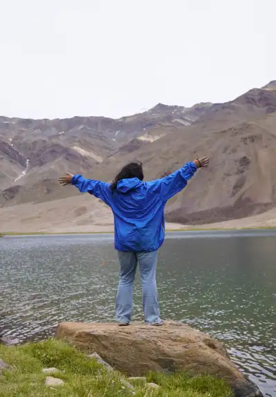 woman spanning her hands wide and overlooking towad Chandrataal Lake, Spiti Valley