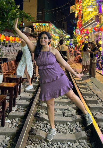 A woman smiling and raising her hand up at Train Street in Hanoi, Vietnam