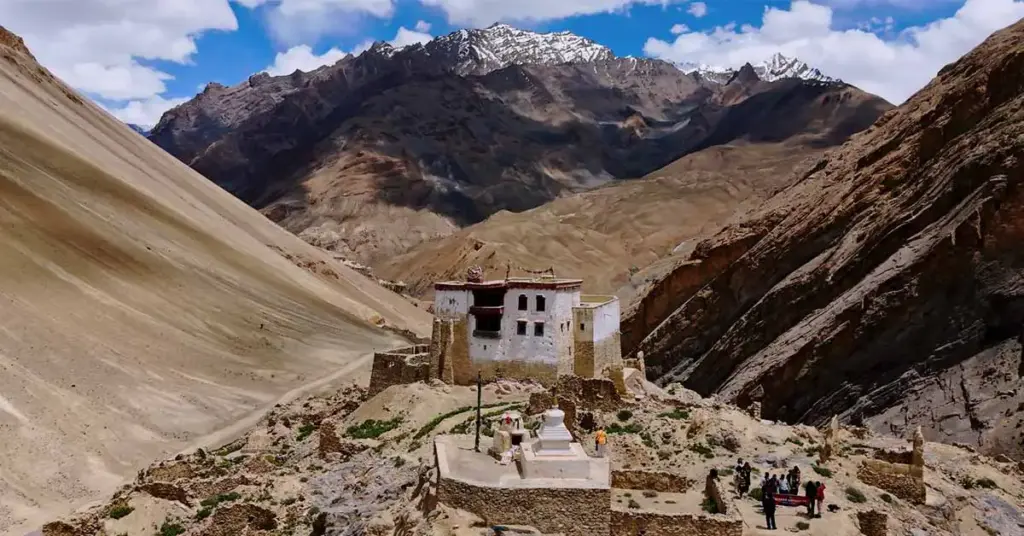 The ancient hilltop fort of Zangla Palace overlooking a rugged desert mountain valley with a traditional white Buddhist stupa chorten in the foreground, a popular tourist attraction in Zanskar, Ladakh.