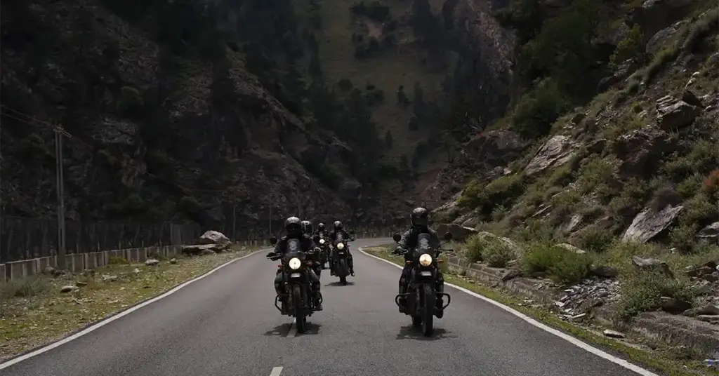 A group of adventure motorcyclists riding along a winding mountain highway in Himachal Pradesh on a Spiti bike trip.