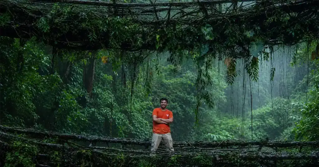Man standing on the Double Decker Living Root Bridge surrounded by rainforest in Meghalaya