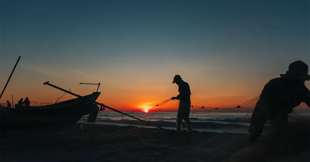 Silhouette of fishermen pulling in a net on a Vietnam beach at sunset