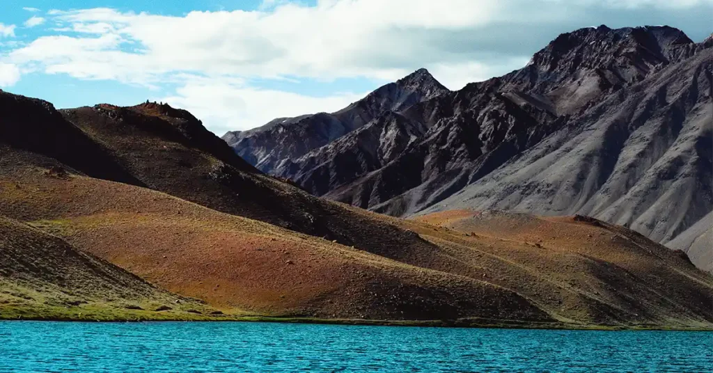 Chandratal Lake at 4,300 m in Spiti Valley, crescent-shaped turquoise water below bare ridgelines near Kunzum Pass