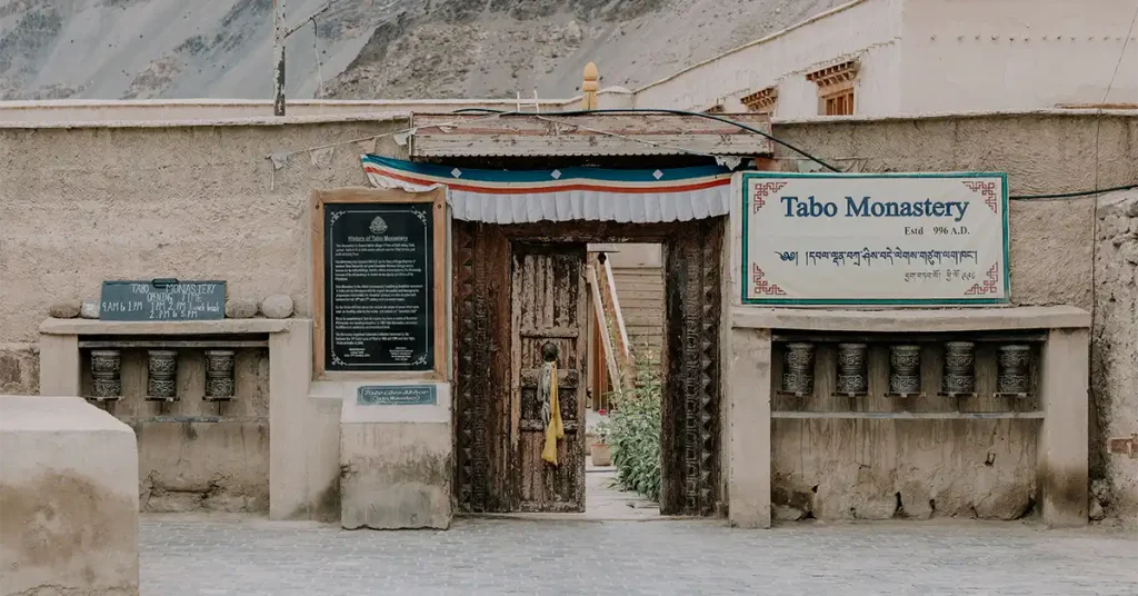 Tabo Monastery entrance in Spiti Valley with prayer wheels and the founding sign reading Estd 996 A.D.