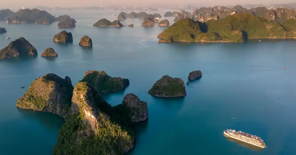 Aerial view of Ha Long Bay's limestone karst islands with a cruise boat, Vietnam
