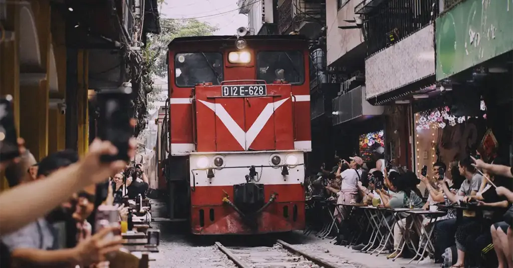 Train passing within inches of cafe tables on Hanoi's Train Street, Vietnam